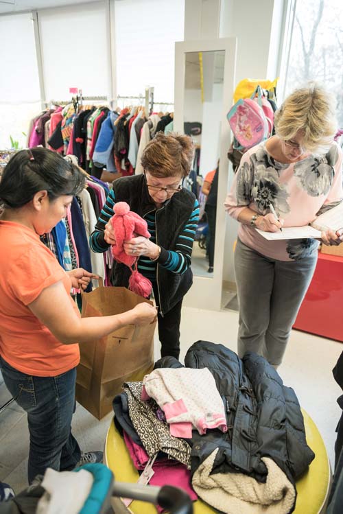 Volunteer shopping assistants work with a client at the Clothes To Kids of Fairfield County Store